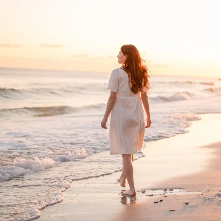 A serene scene of someone walking slowly and mindfully along a beach, focusing on the present moment and embodying intentional living.
